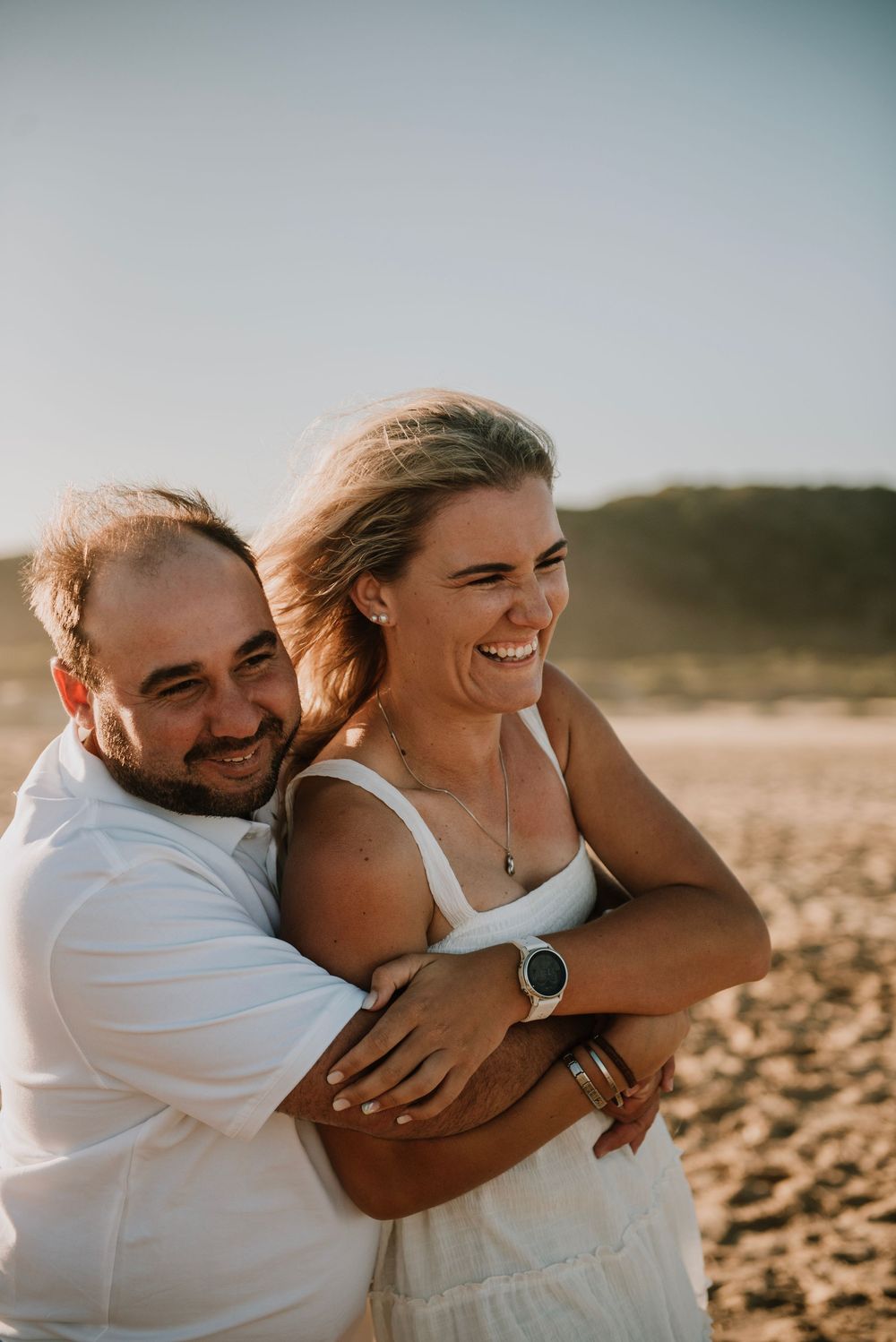 Couple embracing during golden hour with warm sunset light in the background on Hartenbos beach