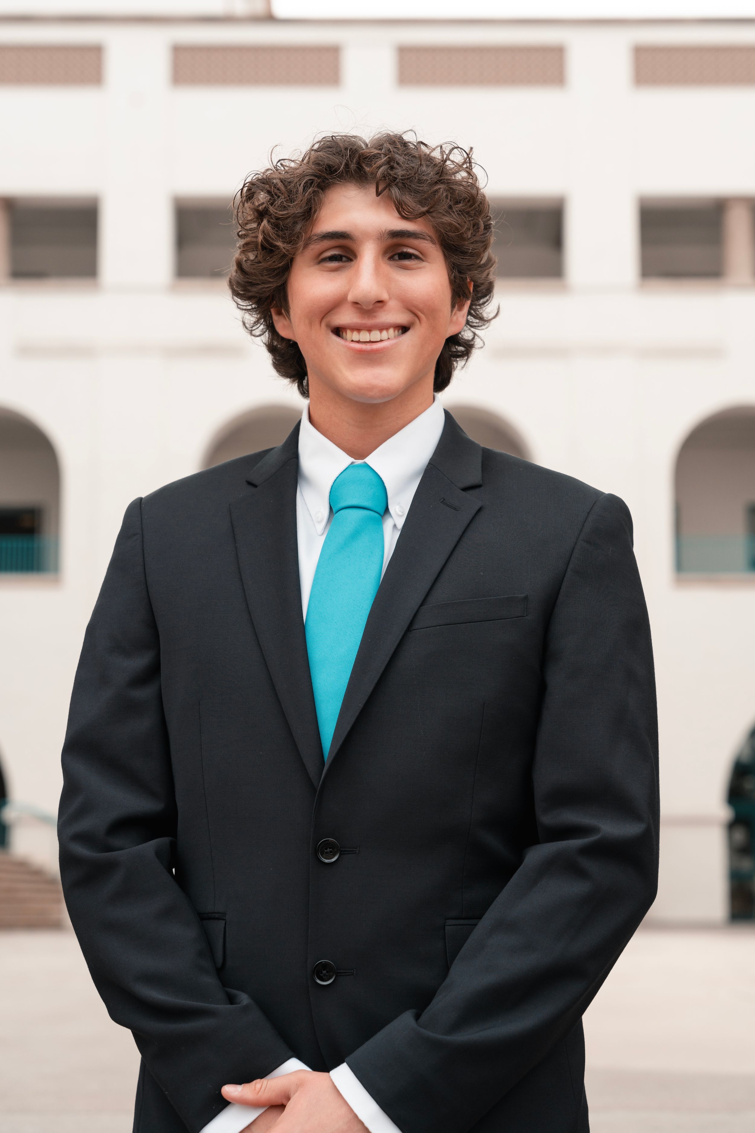 Formal portrait series featuring a graduate in a black suit and turquoise tie.