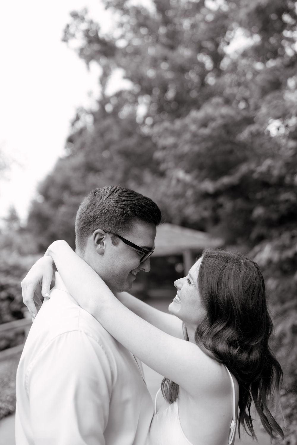 A romantic black and white photo sequence showing a couple sharing an intimate kiss in an outdoor garden setting.
