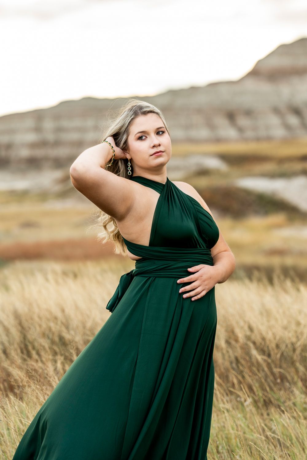 A flowing emerald green dress contrasts beautifully against a rustic outdoor landscape.
