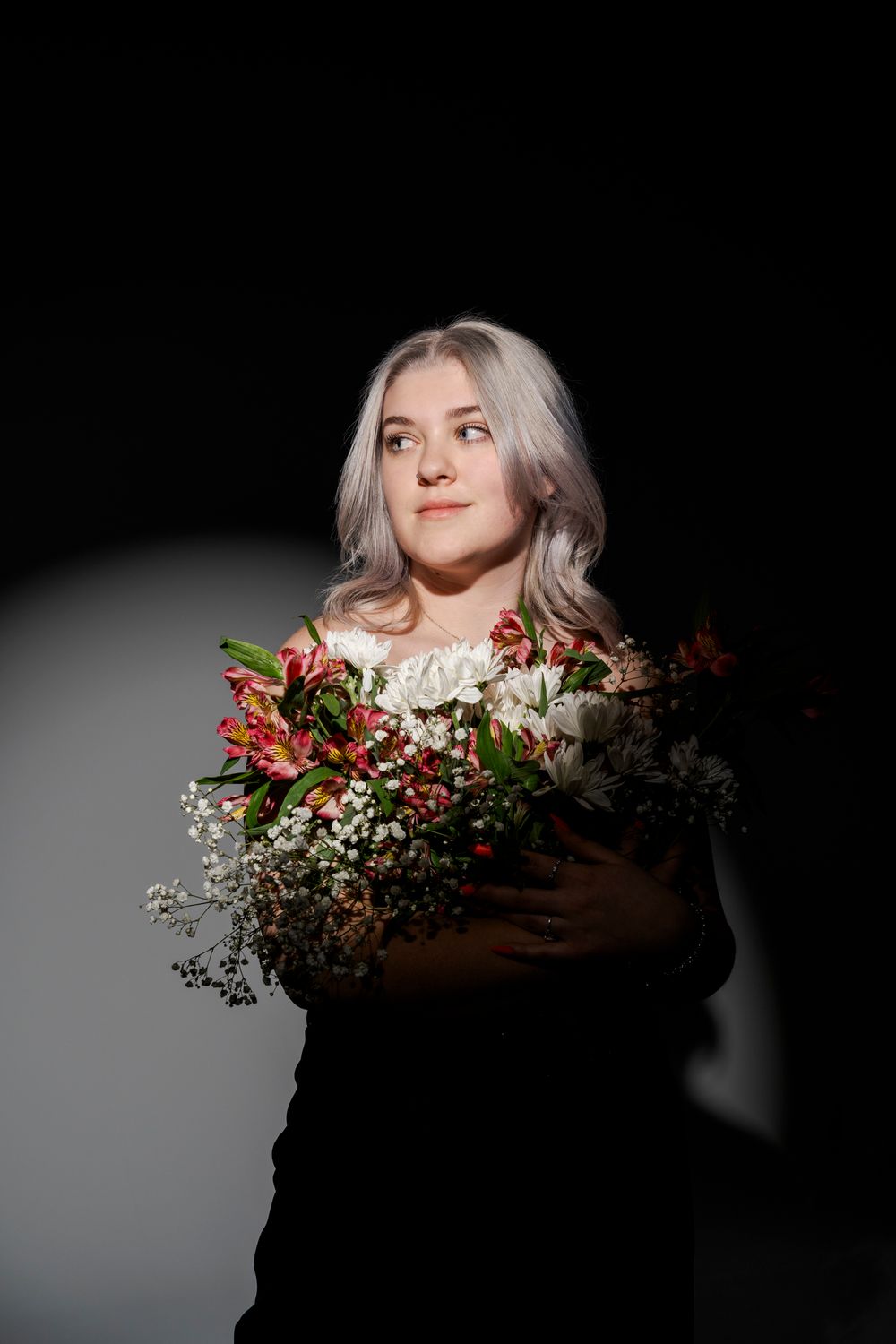 Dramatic portrait with floral arrangements creating an artistic frame in dark lighting.
