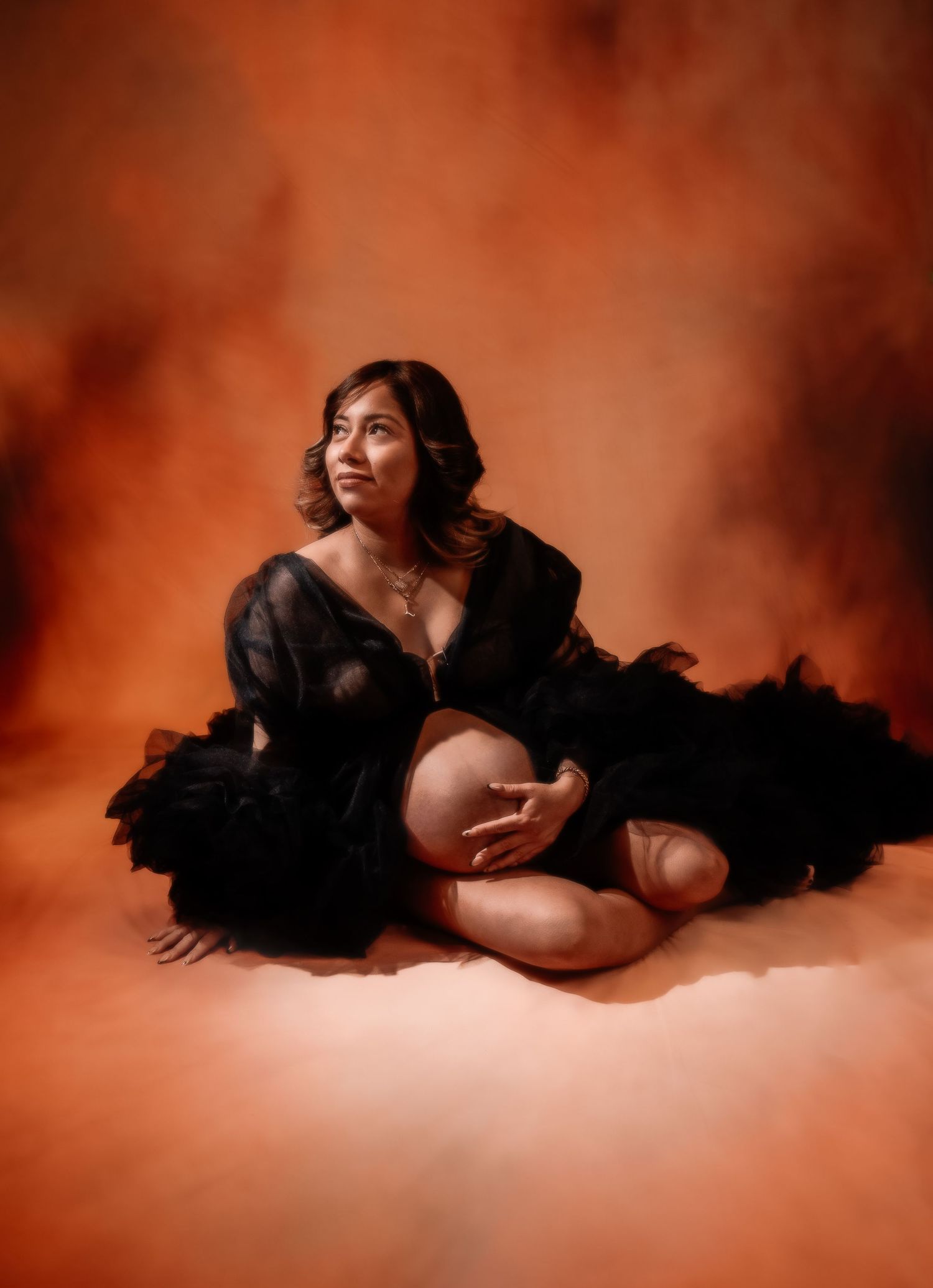 Peaceful sleeping newborn wrapped in black blanket against dark background.
