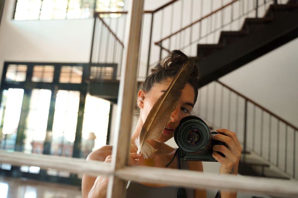 Creative self-portrait through stair railings with camera and natural lighting.