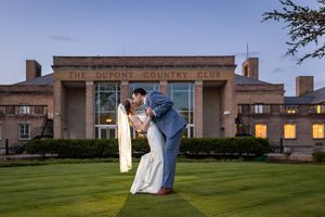 Couple sharing a romantic dip kiss on the lawn at The DuPont Country Club during twilight wedding photos.