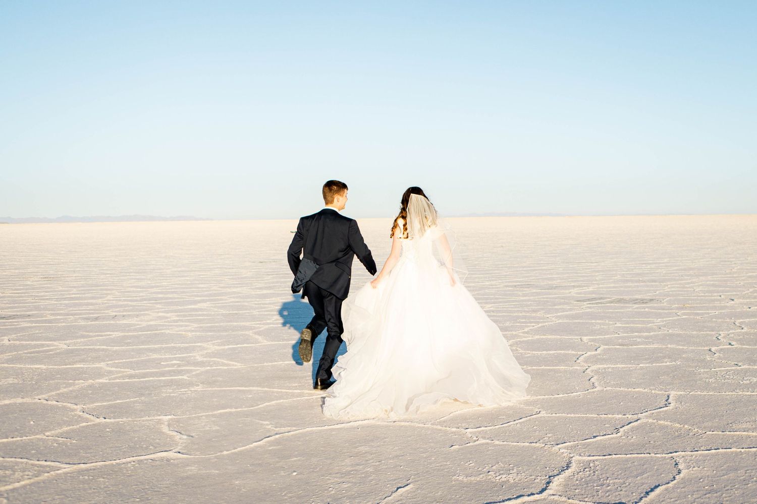 A bride and groom running away at the salt flats