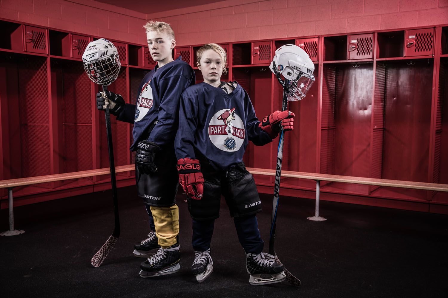 Two FYHA hockey players pose in their red locker room.