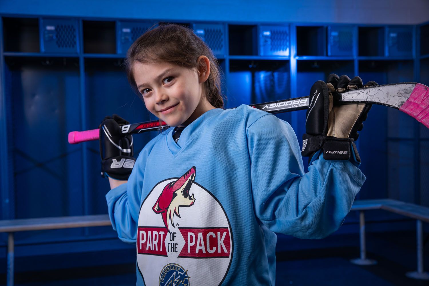 An FYHA hockey player poses in a blue locker room.