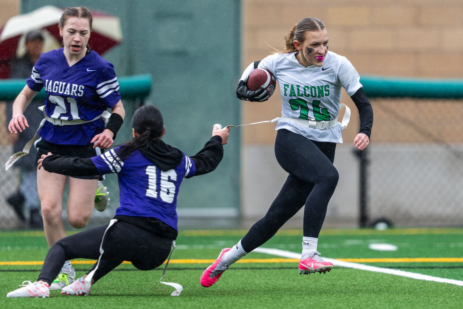 A women's flag football game is played in the rain where a player from Woodinville High School evades a tackle attempt.