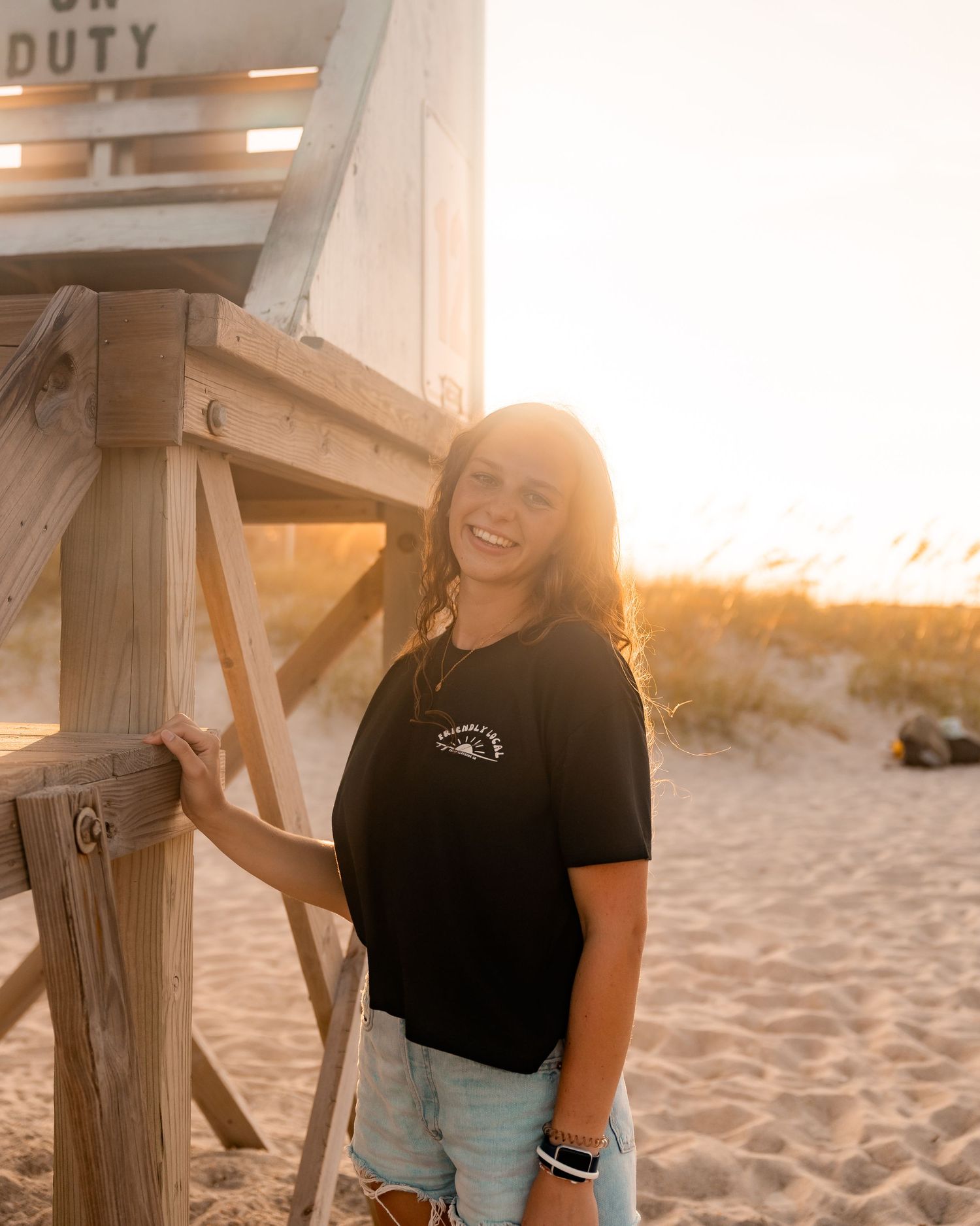 Girl standing on the Wrightsville Beach sand at sunset smilinging towards a camera