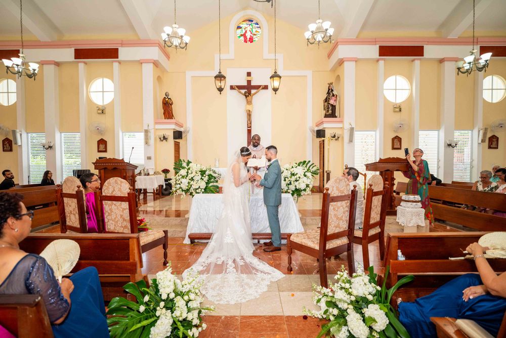 An ornate church interior decorated with flowers and chandeliers during a wedding ceremony.