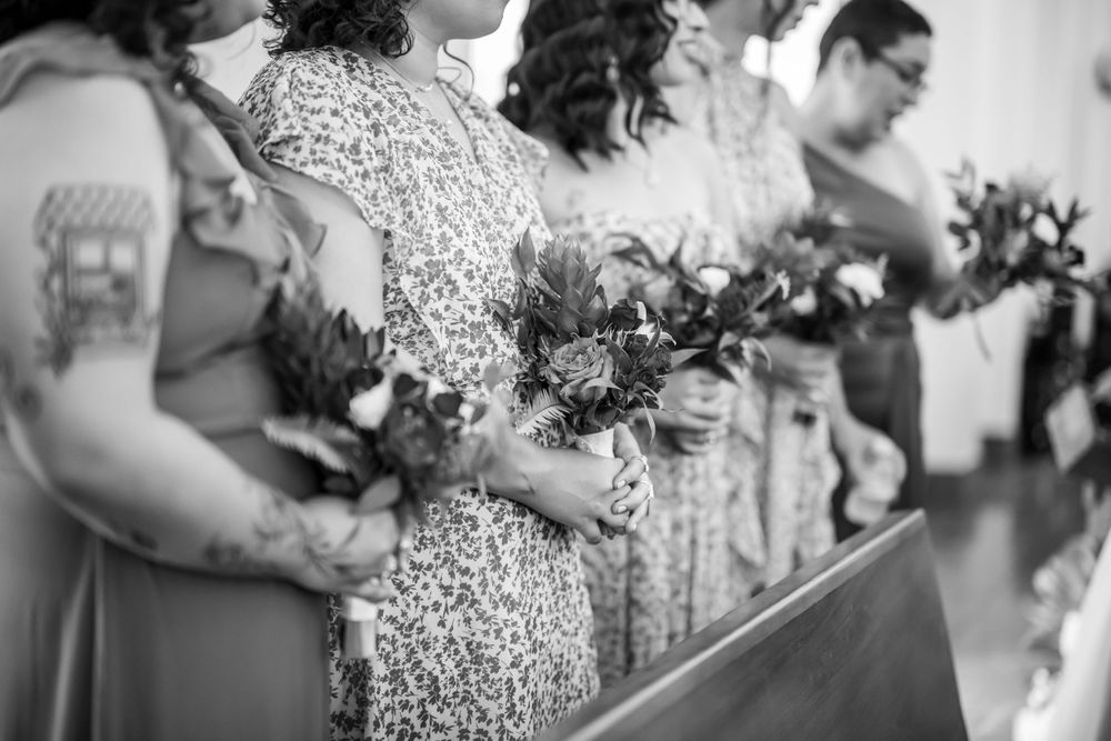 Black and white detail shot of bouquets held by wedding attendants in sequined dresses.