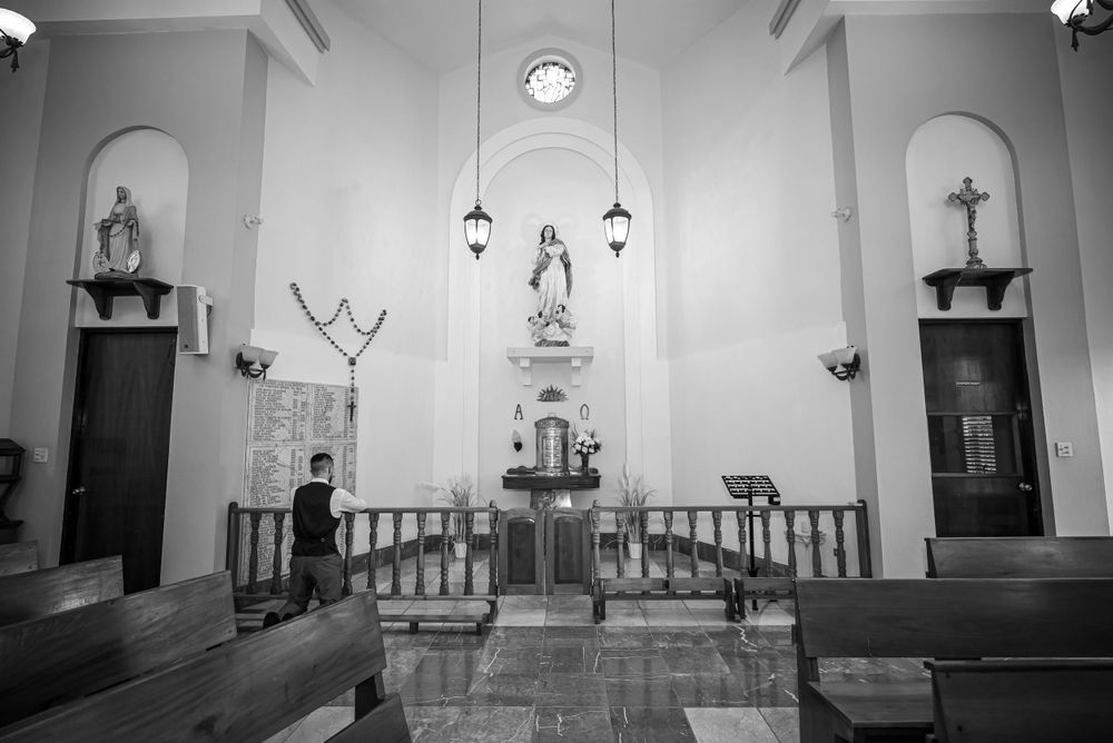 Black and white interior of a Catholic church sanctuary showing religious statues and altar.