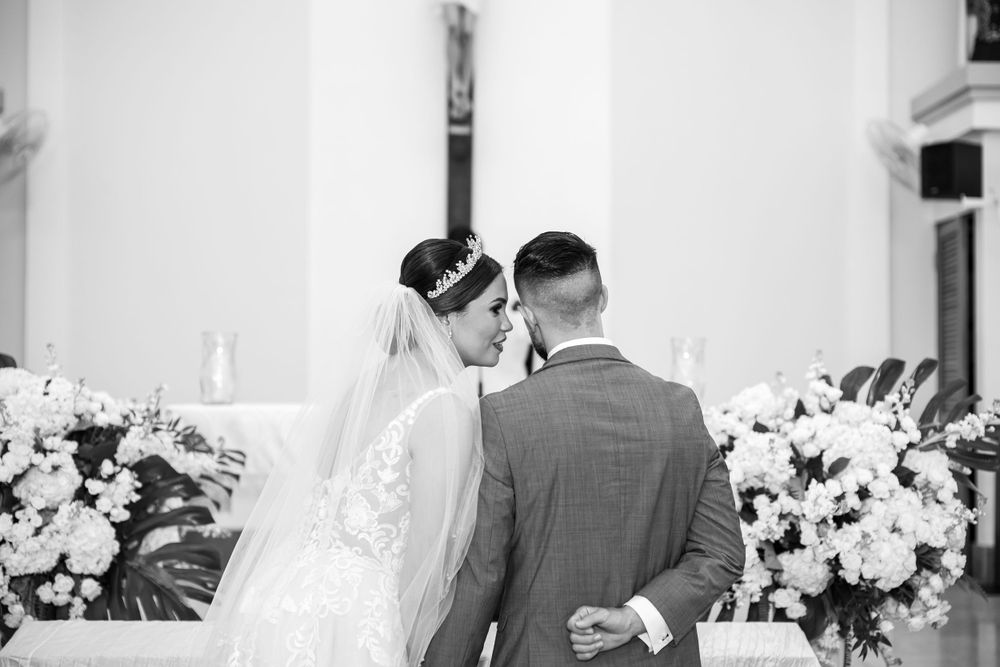 Intimate moment at the altar with a bride's lace veil trailing behind during a church ceremony.