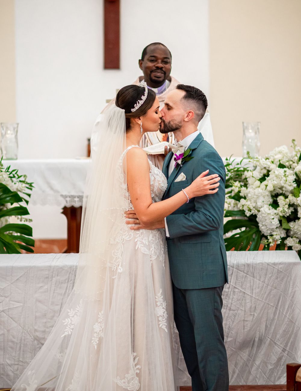 Romantic moment at the church altar surrounded by white flowers and candlelight.