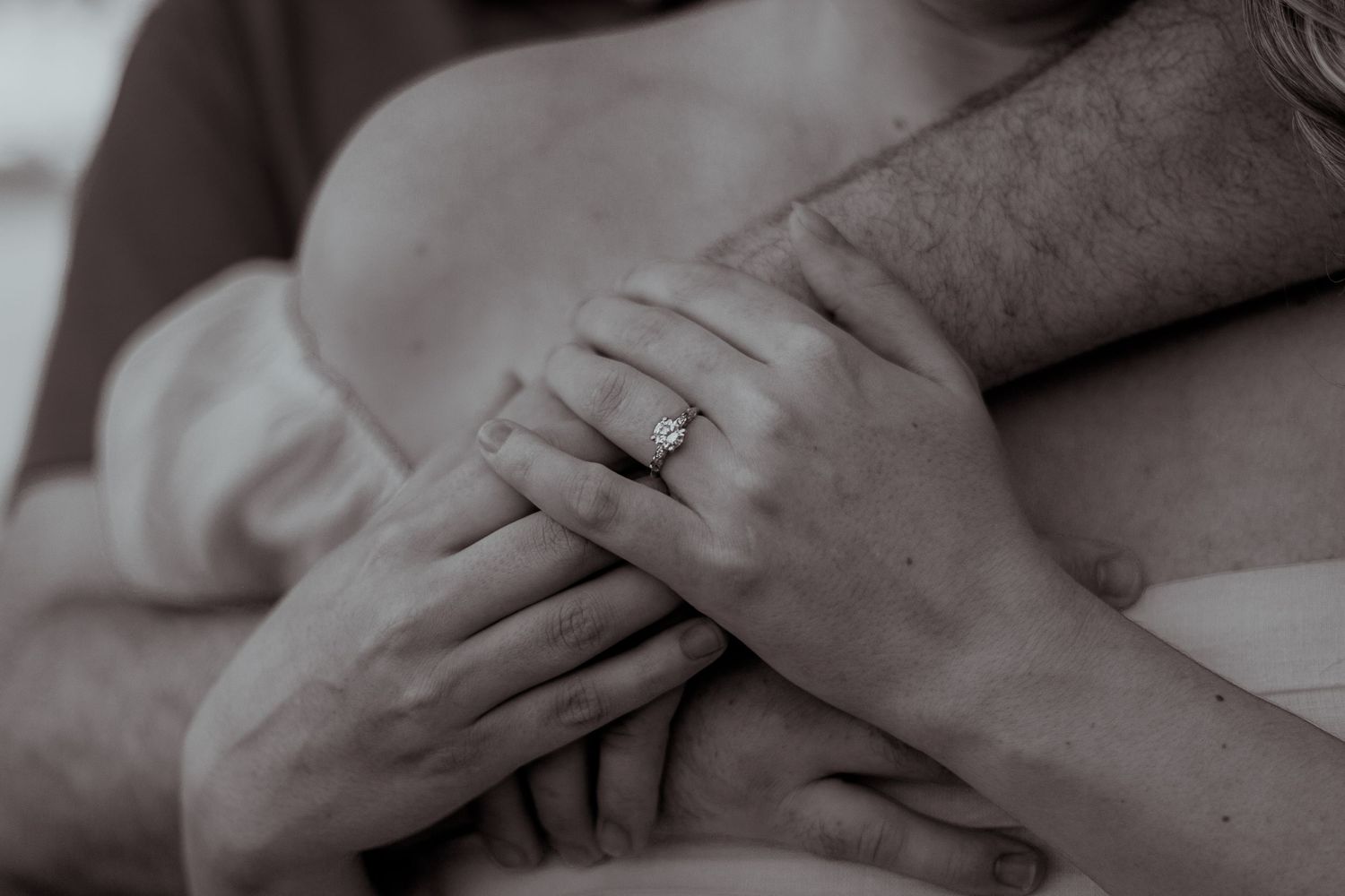 Close up black and white photo of hands with an engagement ring.