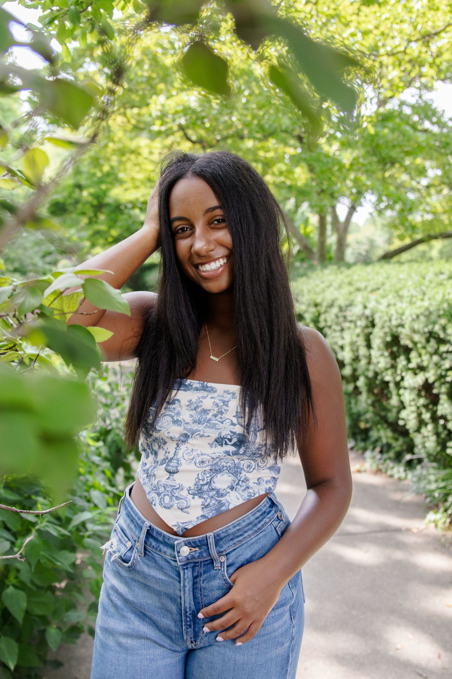 A summer photoshoot in a lush garden featuring casual denim and floral top fashion.
