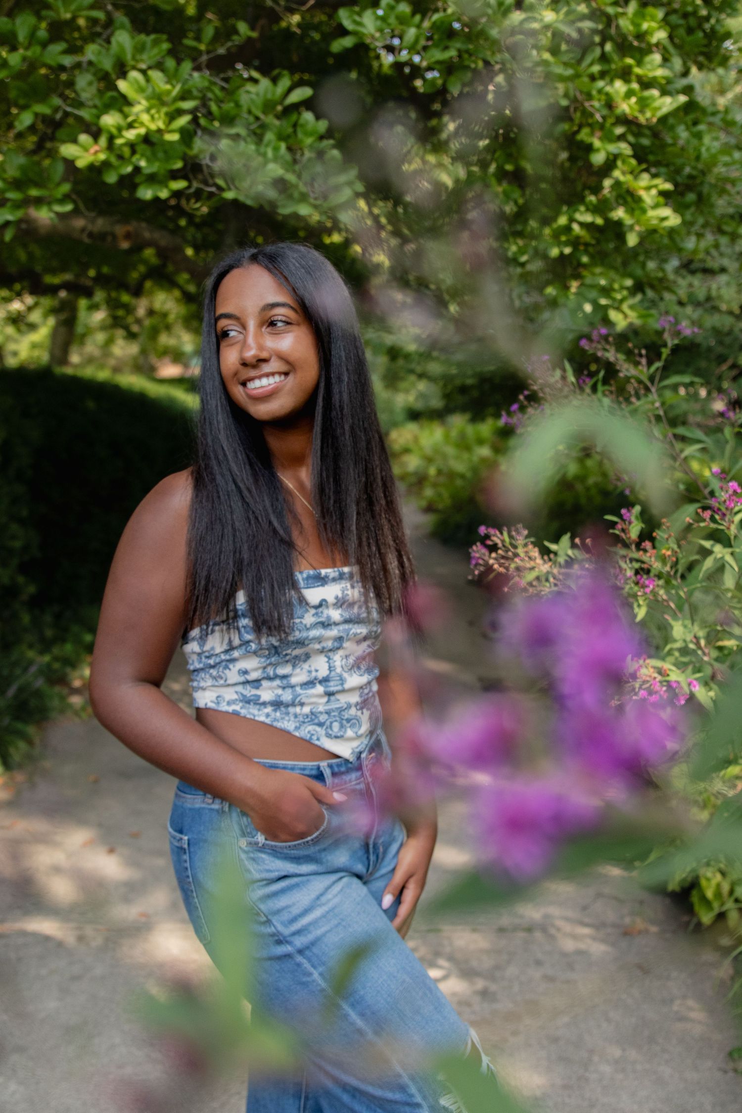 Summer senior portrait session with purple flowers adding color to the natural garden setting.