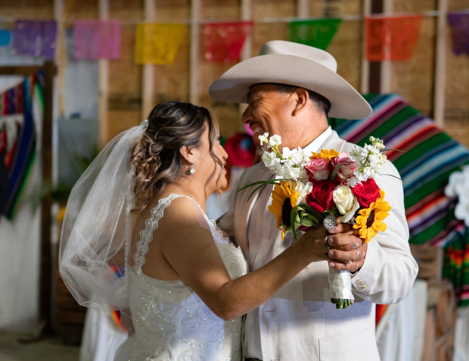 A tender wedding moment captured with colorful Mexican decorations in the background.