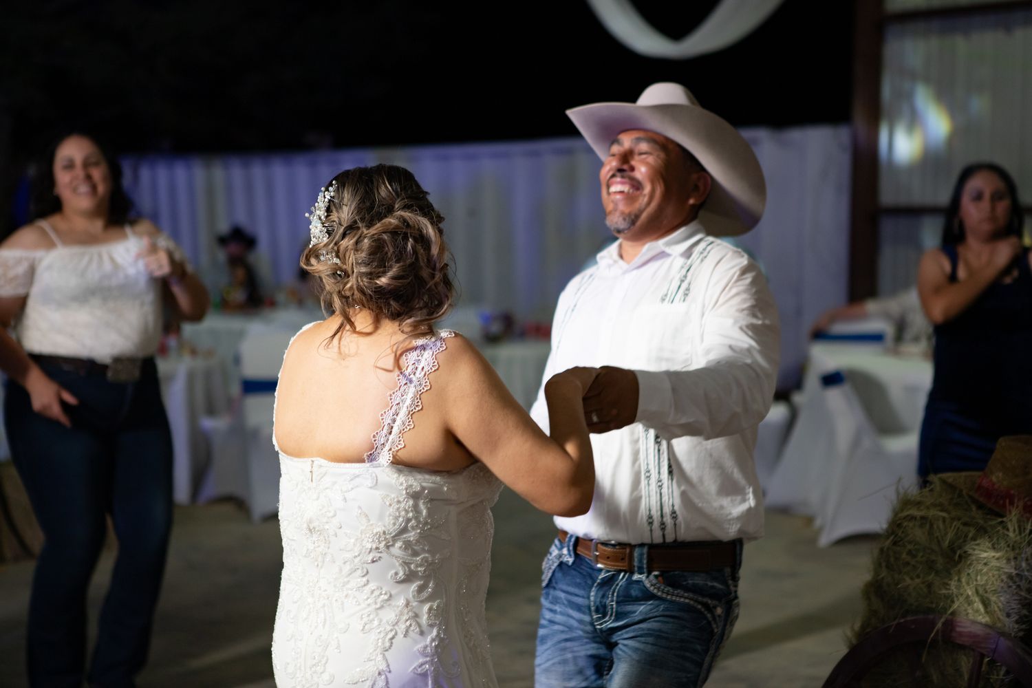 Couple dancing at their wedding reception under colorful papel picado banners.