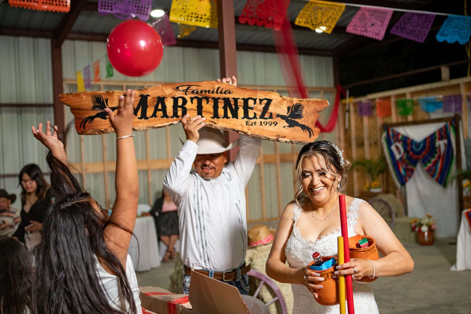 Festive wedding celebration under Martinez sign with papel picado decorations and red balloon.