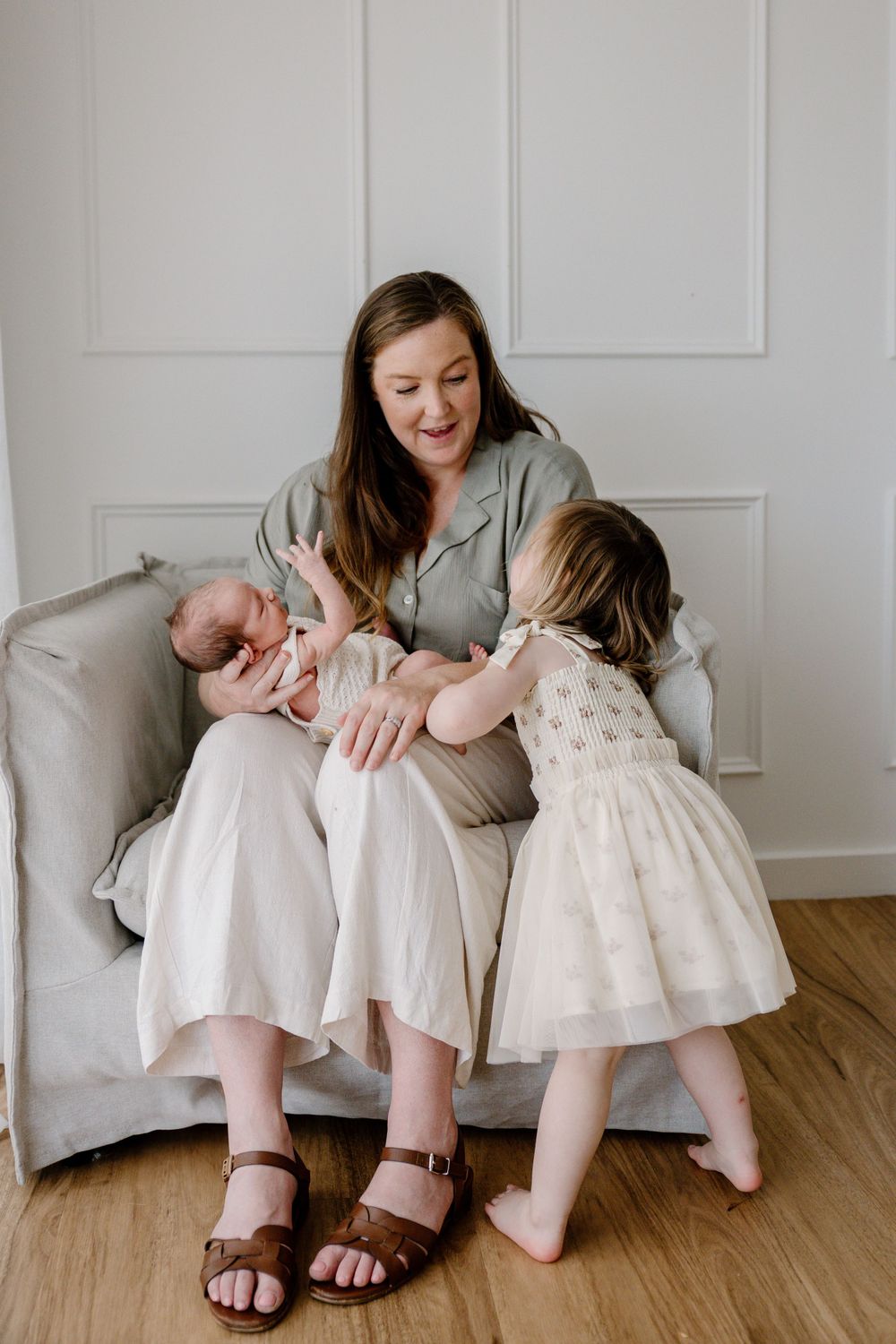 Heartwarming family scene on grey couch with mother and children in soft natural light.