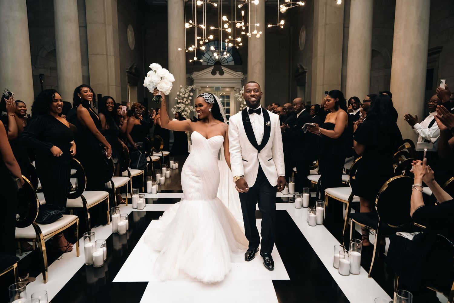 Wedding celebration in modern venue with couple walking down illuminated aisle.