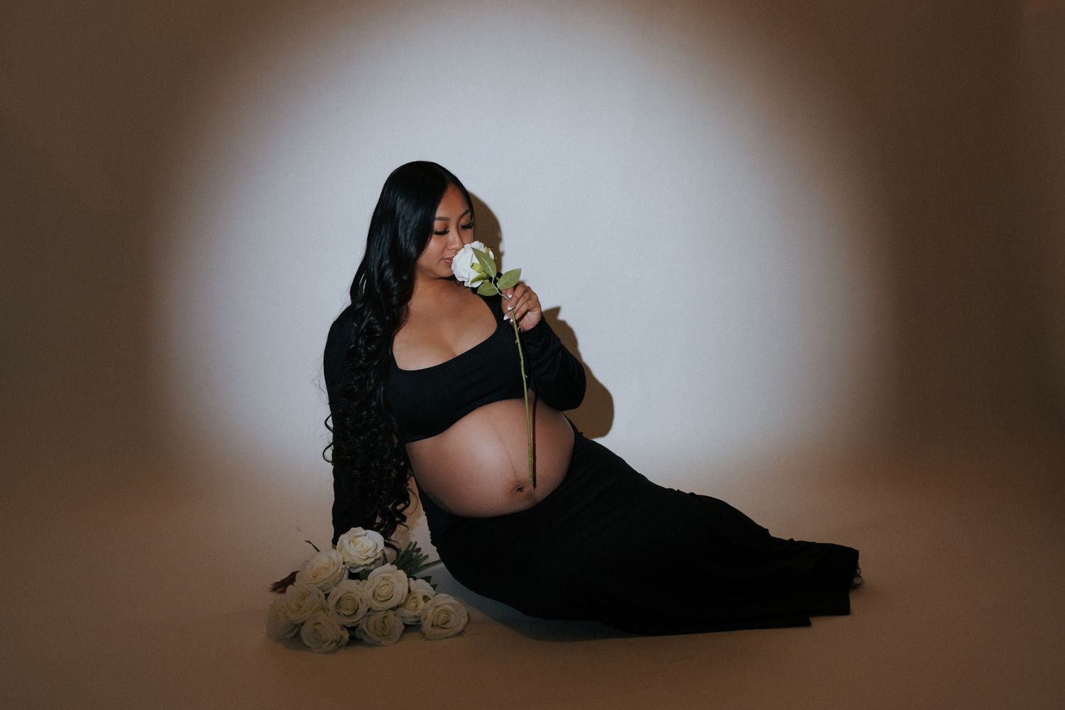 Artistic maternity photos in black dress against dark background.