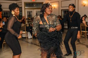 People dancing together at an indoor event venue with warm lighting and elegant decor.