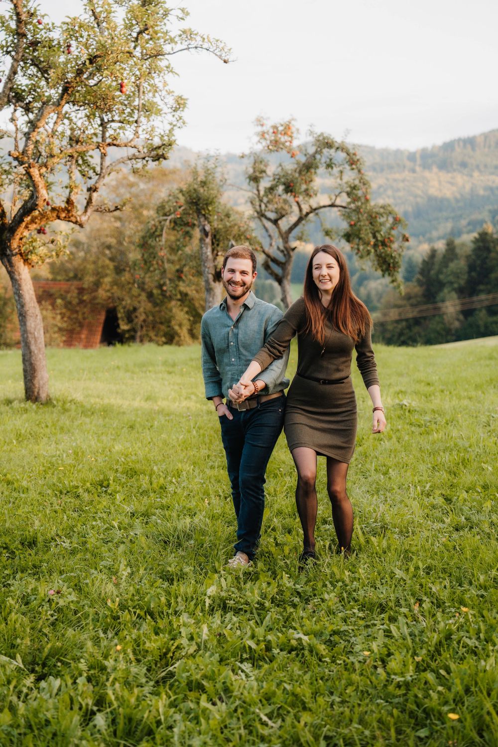 Couple walking and laughing together in a scenic mountain meadow during autumn.