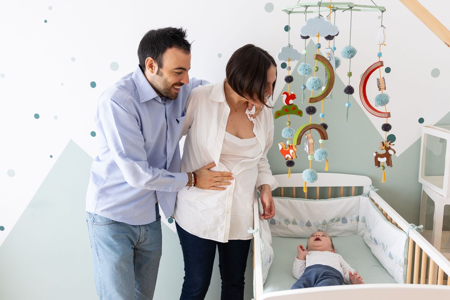 Parents sharing a happy moment while looking into baby crib with mobile decorations.
shooting embarazo
fotógrafa de familia sevilla
shooting