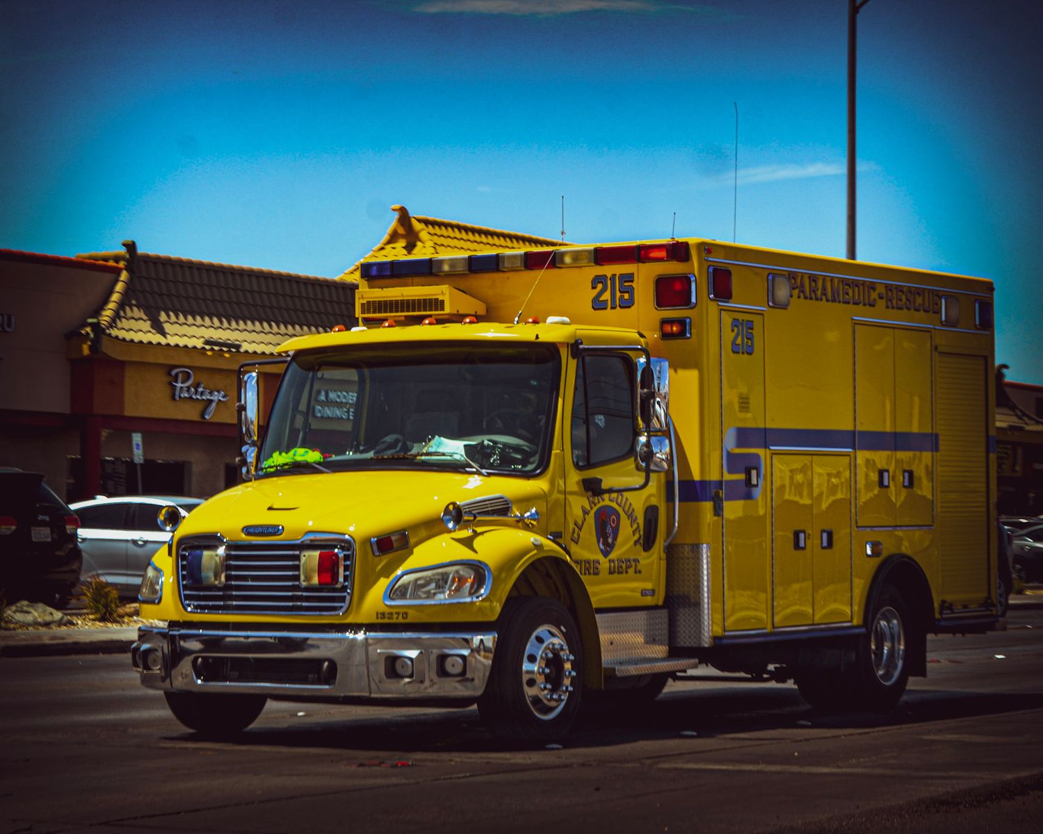 Yellow emergency response vehicle parked in a lot against blue sky.