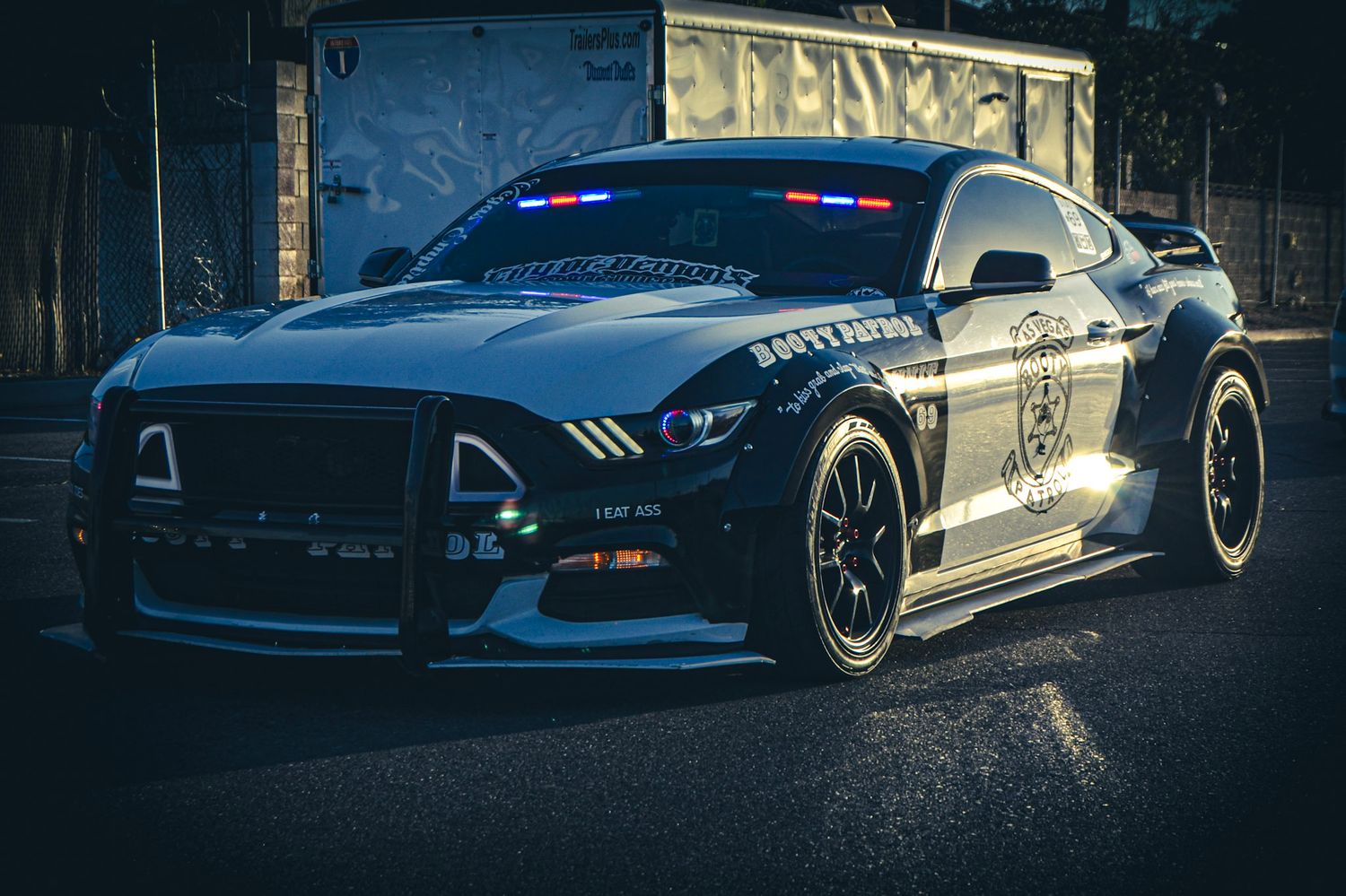 Black Ford Mustang police vehicle with custom modifications parked in dark setting.