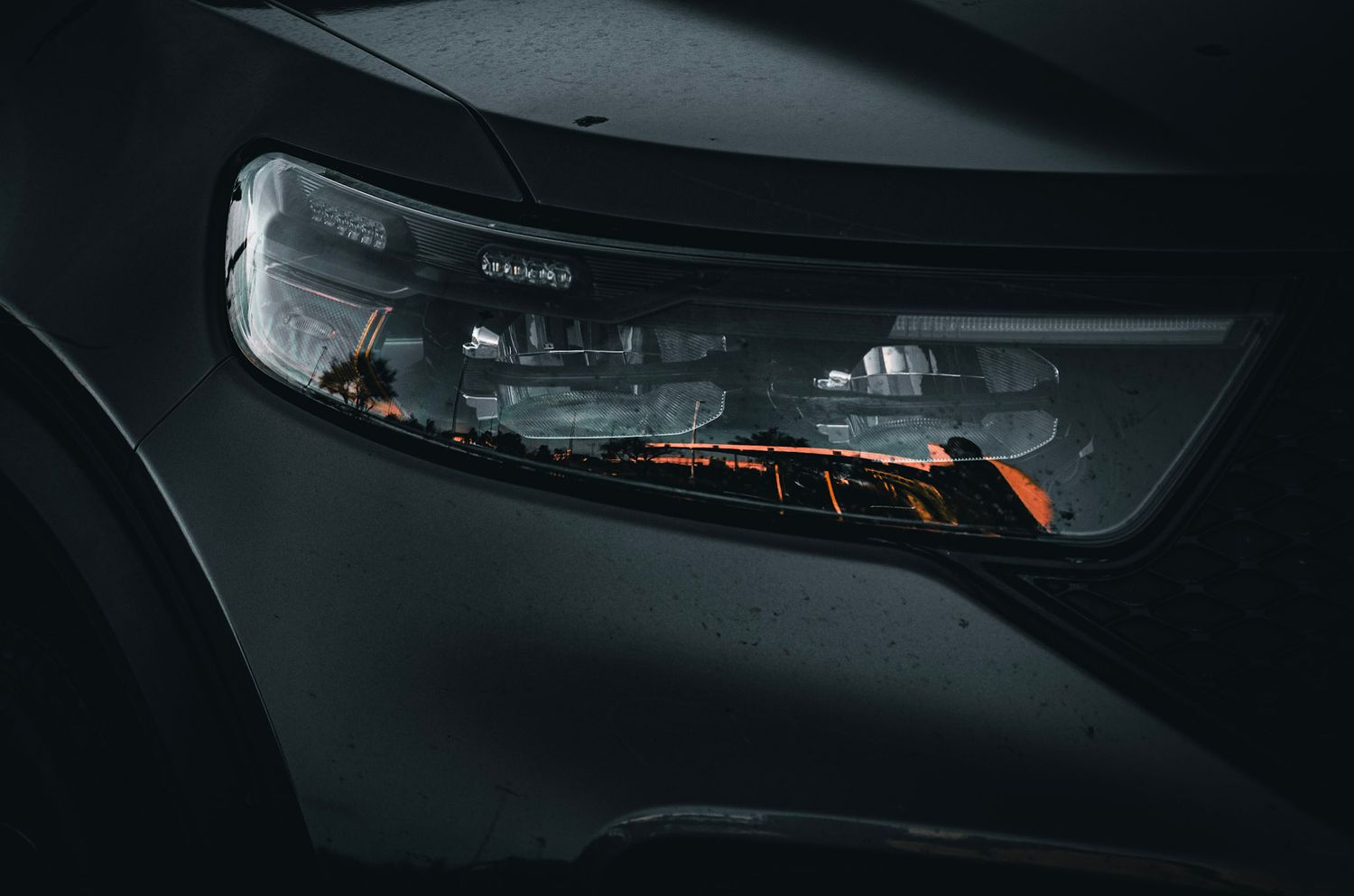 Close-up detail of modern car headlight assembly in dark setting.