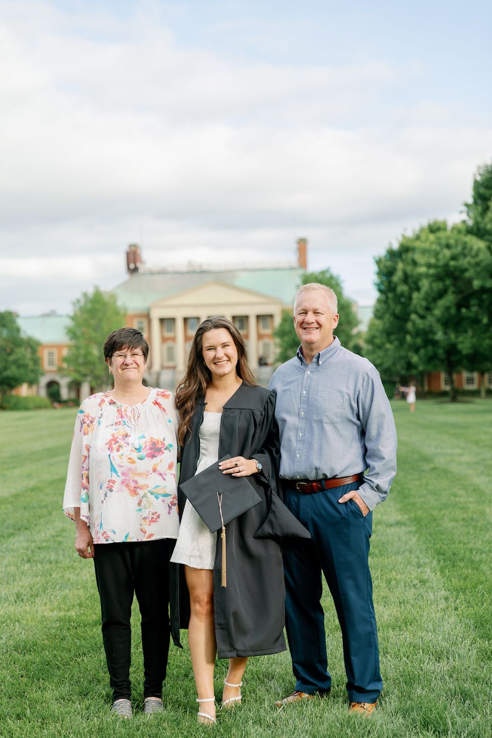 Graduation celebration on green lawn in front of historic brick building.