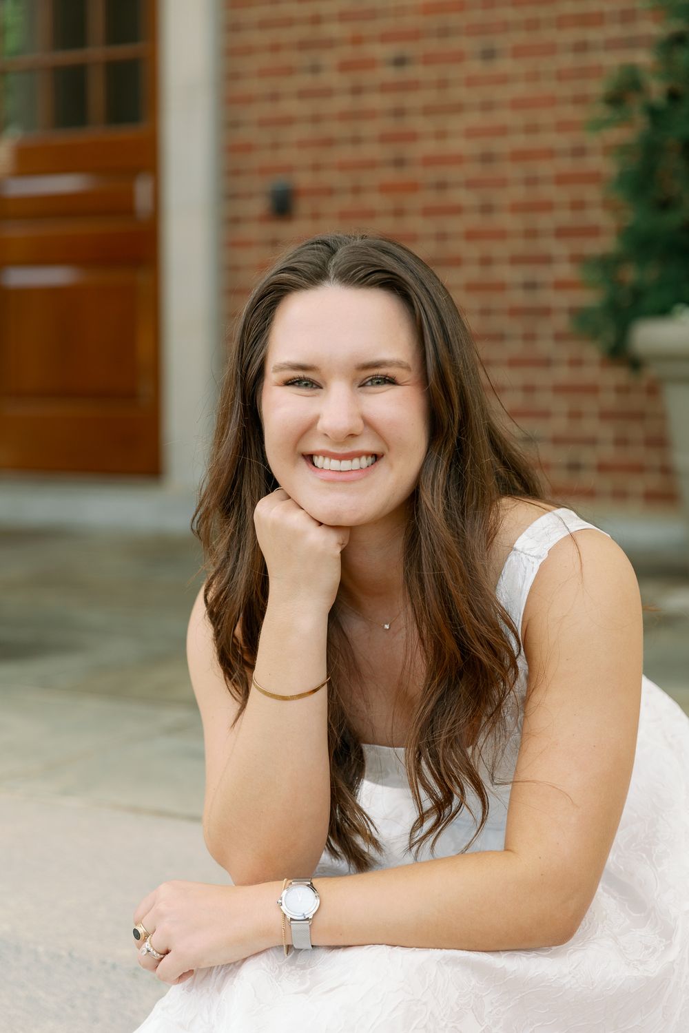 Casual portrait session on a stone porch with brick walls and white columns.