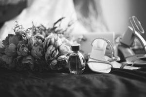 Black and white photo of wedding bouquet and bridal shoes in artistic composition.