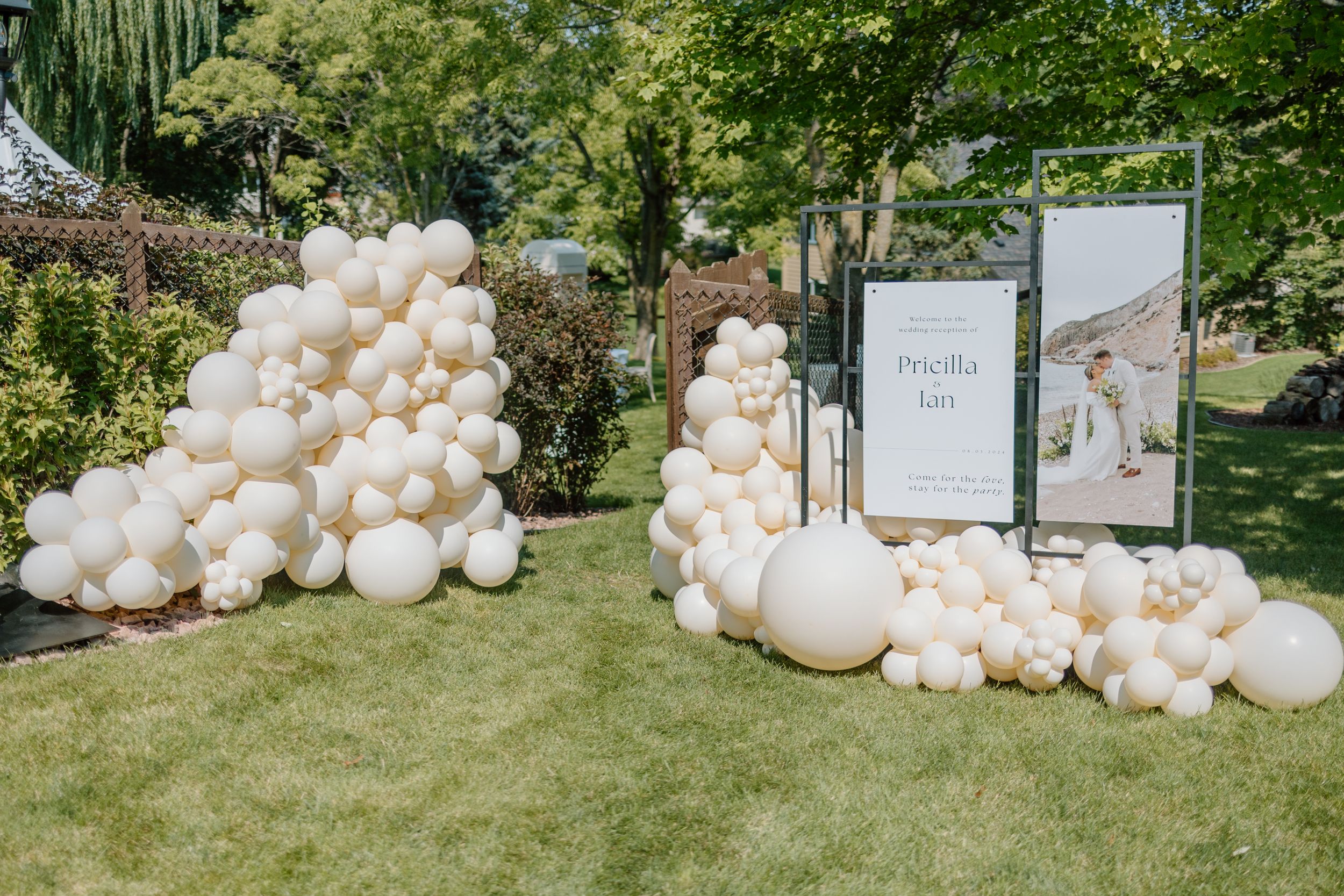 Luxurious white balloon arch installation with signage for wedding decor.
