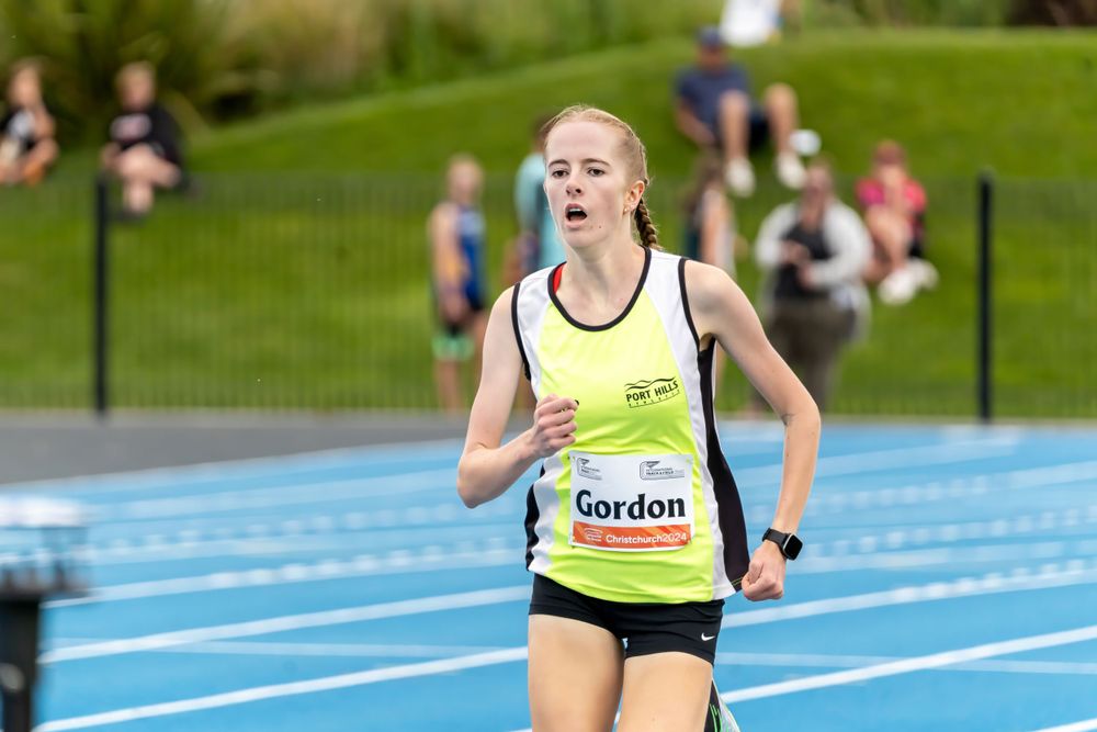 Track athlete runs intensely on a blue running track during an outdoor competition event.