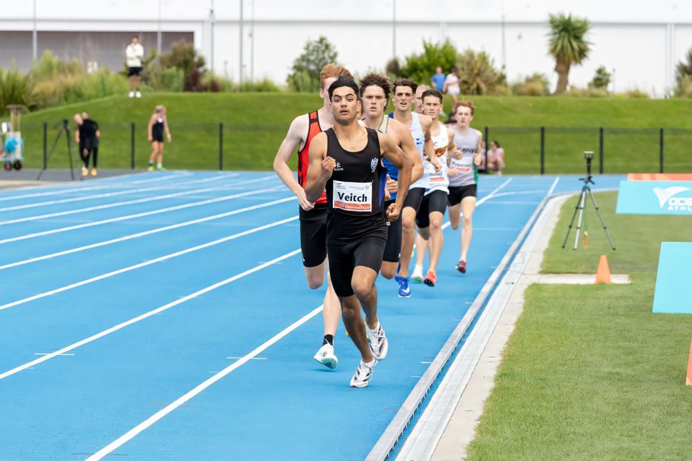 Runners compete on blue track during outdoor athletics competition.