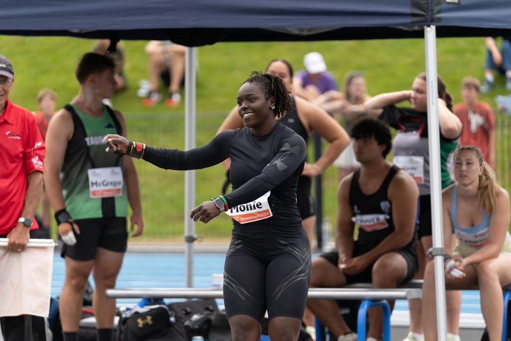 Athletes prepare under tent during outdoor track meet competition.