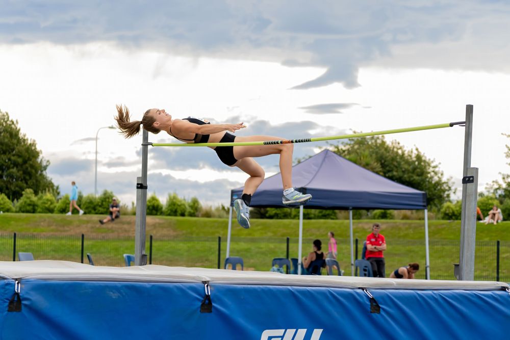 High jumper arching over bar during outdoor track and field competition.