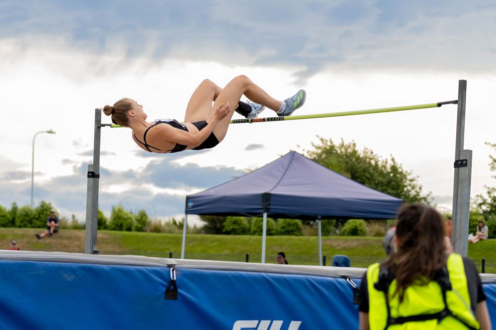 High jumper executing back arch over bar during outdoor track meet.