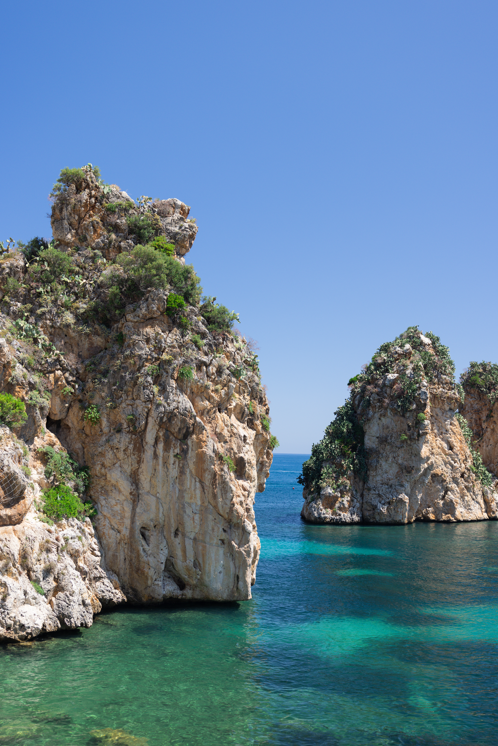 Dramatic limestone sea stacks rising from crystal clear turquoise Mediterranean waters.