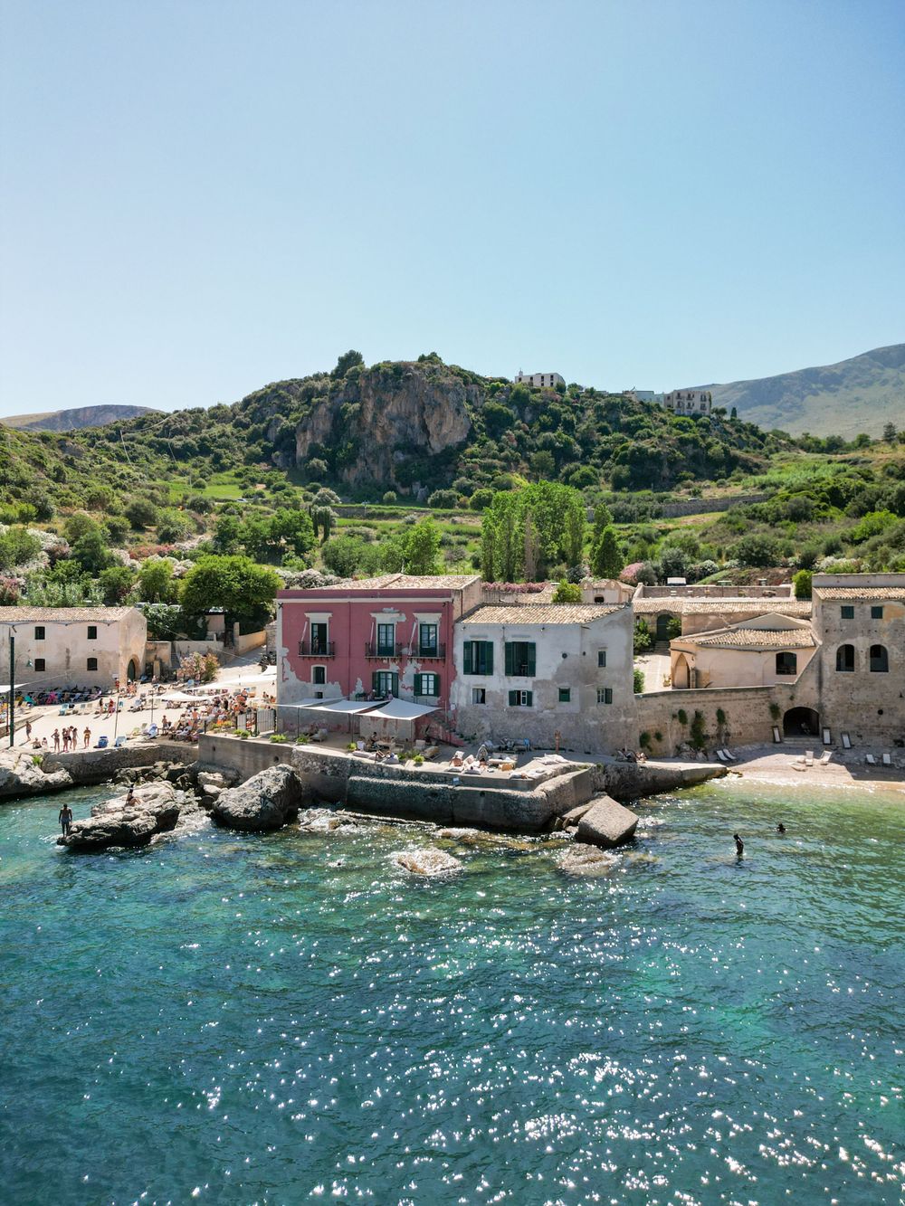 Coastal village with colorful buildings and boats anchored in crystal clear Mediterranean waters.