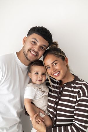 Happy family with a smiling holding their baby, posing together against a white background Nottingham birthday photoshoot