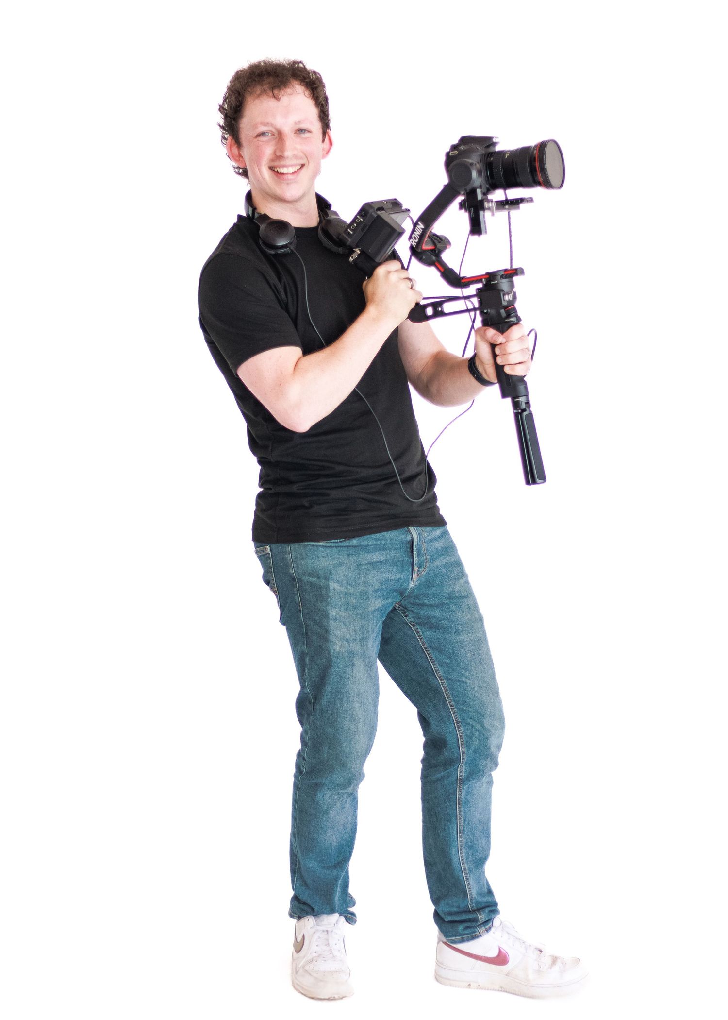 A photographer holds a camera lens while posing against a dark background.