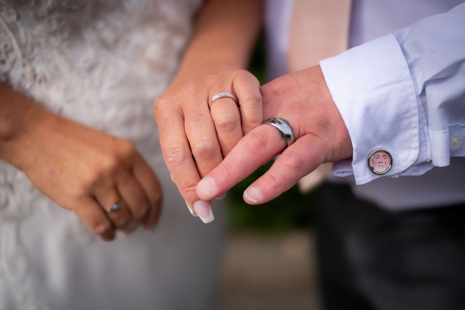 Close-up of newlywed hands showing wedding rings against a soft background.