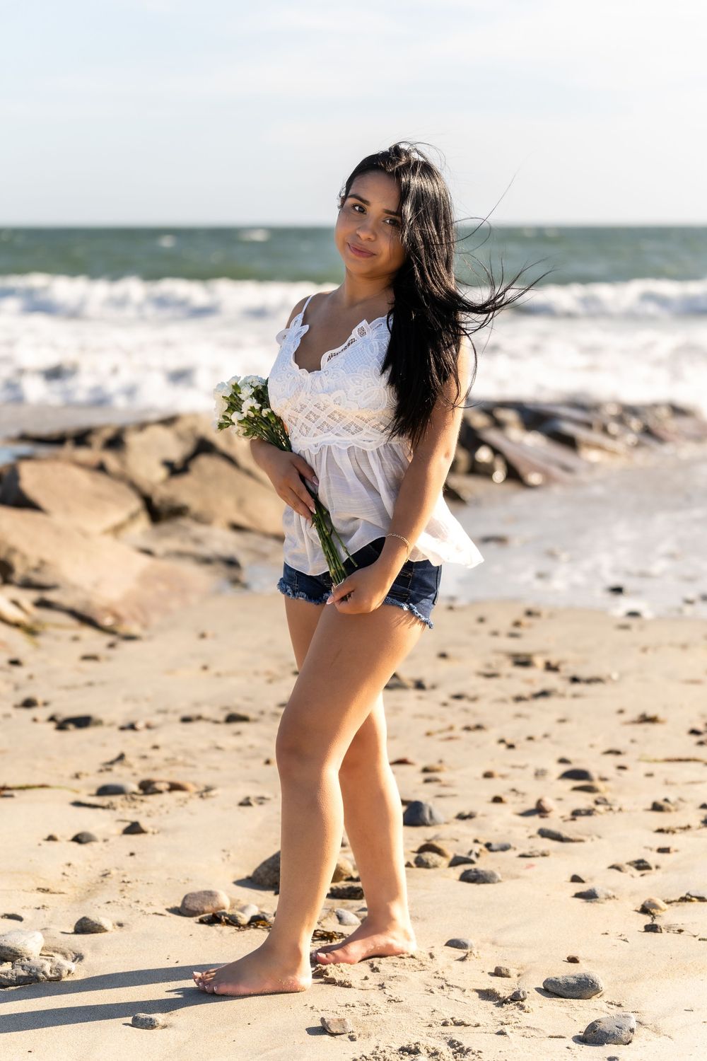 Summer beach photoshoot with waves and rocky shoreline.