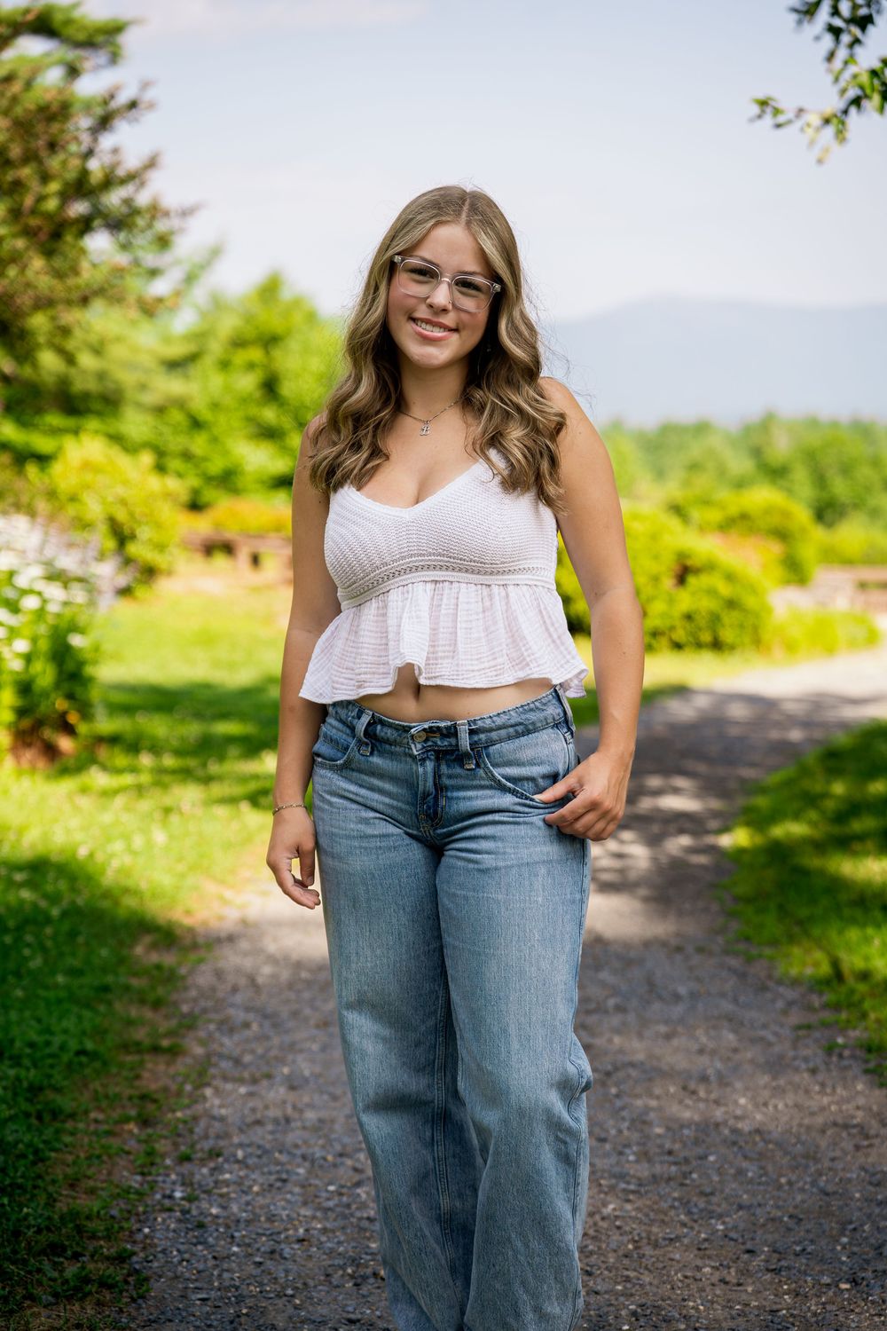 Casual outdoor portrait featuring denim jeans and a white top on a gravel path.