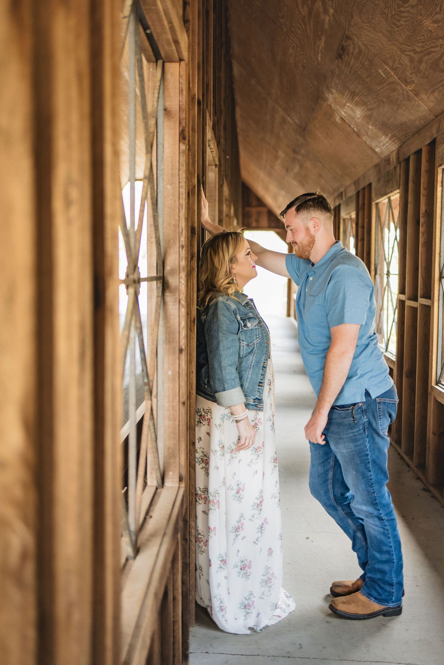 A couple shares an intimate moment in a sunlit wooden hallway.